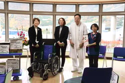 車いすを寄贈する牧野総支部長（左から２人目）青木副総支部長（左）と熊木院長（右から２人目）