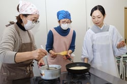 「きのこのリゾット」の調理法を受講生に伝える中村さん（右）