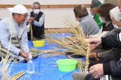 講師（左）から「わら」のより方を教わる参加者