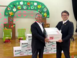 りんごを手渡す黒岩修一部会長（左）と受け取る竹内延彦教育長（右）