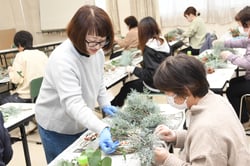 花材を束ねてリースを作る参加者と講師