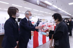 理事から福だるまを受け取る来店客