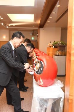 豊作と目標達成を祈願して目を入れる栗林組合長ら