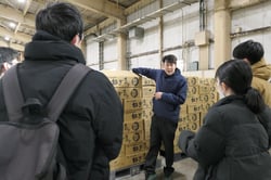 集荷センターでねぎの販売について説明する職員