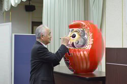 だるまの目入れをする下島専務理事