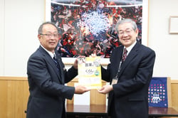 教材を熊谷教育委員長へ手渡す中村組合長（左）