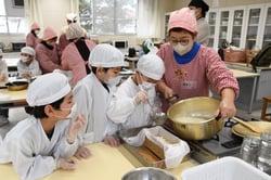 固まった豆乳を豆腐箱に入れる児童
