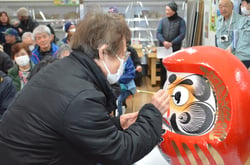 だるまの目入れをする生産者