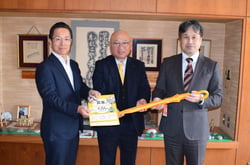 教材を手にする須山校長（右）と望月隆組合長（中央）