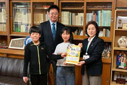 教材を手渡すＪＡ大北の松澤理事（右）と5年生代表の高橋さん、宮沢校長、浅野さん(20日長野県白馬村で)