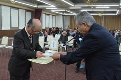 西村組合長（右）から表彰状と記念品を受け取る生産者（長野県伊那市で）