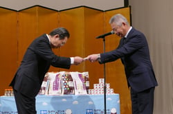 碓井理事長（左）に目録を手渡す根津副本部長