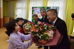 アルストロメリアの花束を受け取る代表児童（左）（長野県伊那市で）