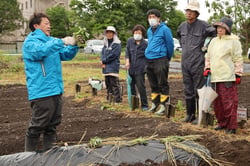参加者にサツマイモの定植方法を伝える森山所長代理（左）（長野県岡谷市で）