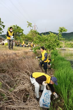トングを使って諏訪湖畔に落ちているごみを拾う職員（長野県諏訪市で）