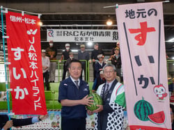 西澤智成社長（左）にすいかを手渡す田中組合長（右）（１２日、長野県松本市で）