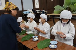 部員の手ほどきで餡を包む児童