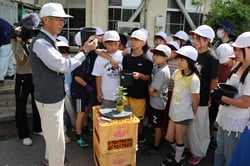 健香会の奥山顧問（左）からドーム菊の植え方を教わる中洲小４年生（長野県諏訪市で）