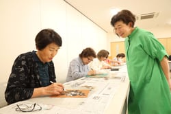 日達さん（右）が見守る中、切り絵を楽しむ部員（長野県茅野市で）
