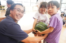園児にスイカを贈る堀井青壮年部長（松本市梓川）