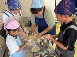 講師（中央）の手元を見ておやき作りに挑戦する参加者（長野県上田市で）