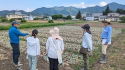 ほ場視察で生産者（左）の話を熱心に聞く受講者（長野県上田市で）