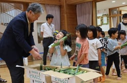 うれしそうにトウモロコシを受け取る園児