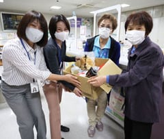 家庭で余っている食材を生活就労支援センターの支援員に手渡す宮坂支部長（右）と北澤和子副支部長（右から2番目）