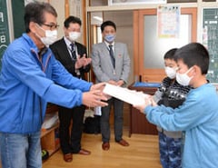 児童へ紅白もちを手渡す西澤農家組合長