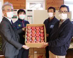 百瀬教頭（左）にリンゴを手渡す村山支部長（右）と上條部会長（右から2番目）