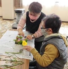 久保講師（奥）の指導で花を飾り付ける参加者