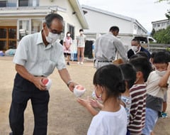 園児代表にモモを渡す山﨑支部長
