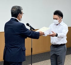 田中組合長から支援金を受け取る中村さん（右）