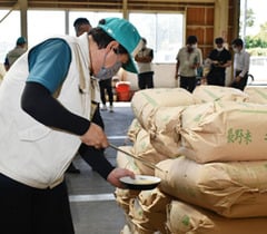 殻刺しで抜き出した玄米の水分量を計測する勝野検査員（中）