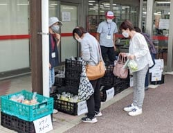 アグリながぬまでリンゴを配布する組合員（左）と買い物客