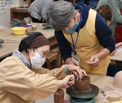 講師（右）のアドバイスを聞き、成形する部員（左）
