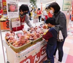 味の特徴を聞いてリンゴを買い求める親子連れ
