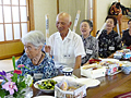 丸めた新聞紙で隣の人の肩をたたき合うゲームで楽しむ参加者