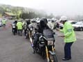 ライダーに交通安全を呼びかけエノキタケを手渡す警察官