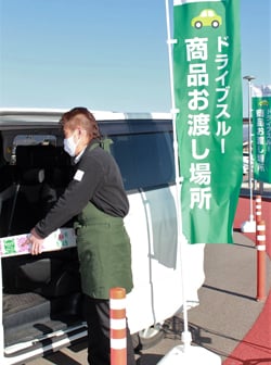 利用者の車両に商品を積み込む道の駅スタッフ