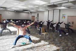ストレッチ体操で思い切り手足を広げる参加者