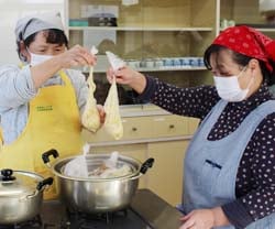 料理のできを確認する生活指導普及員（左）と部員（右）
