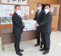 小松副町長（左）にリンゴを手渡す小坂部会長（中央）と徳竹地区担当理事