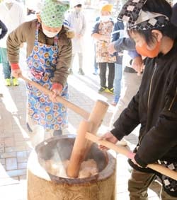 杵と臼を使って餅をつく児童