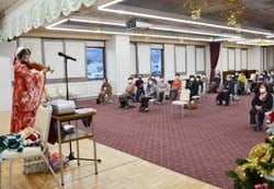 ステージでバイオリンを演奏する牧さんの曲に聞き入る参加者