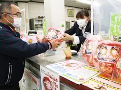JA職員からだるまを受け取る利用者（諏訪支所）
