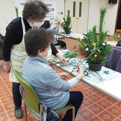 フラワーアレンジメントに挑戦する部員（右）とアドバイスする西澤さん