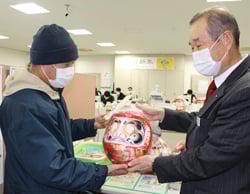西村副組合長（右）から福だるまを受け取る組合員
