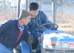 大月さんに（右）トラクターの操作方法を指導するJA農業機械担当職員