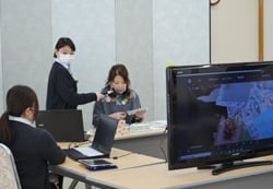 クリップボードを製作する吉沢さんと配信する職員ら